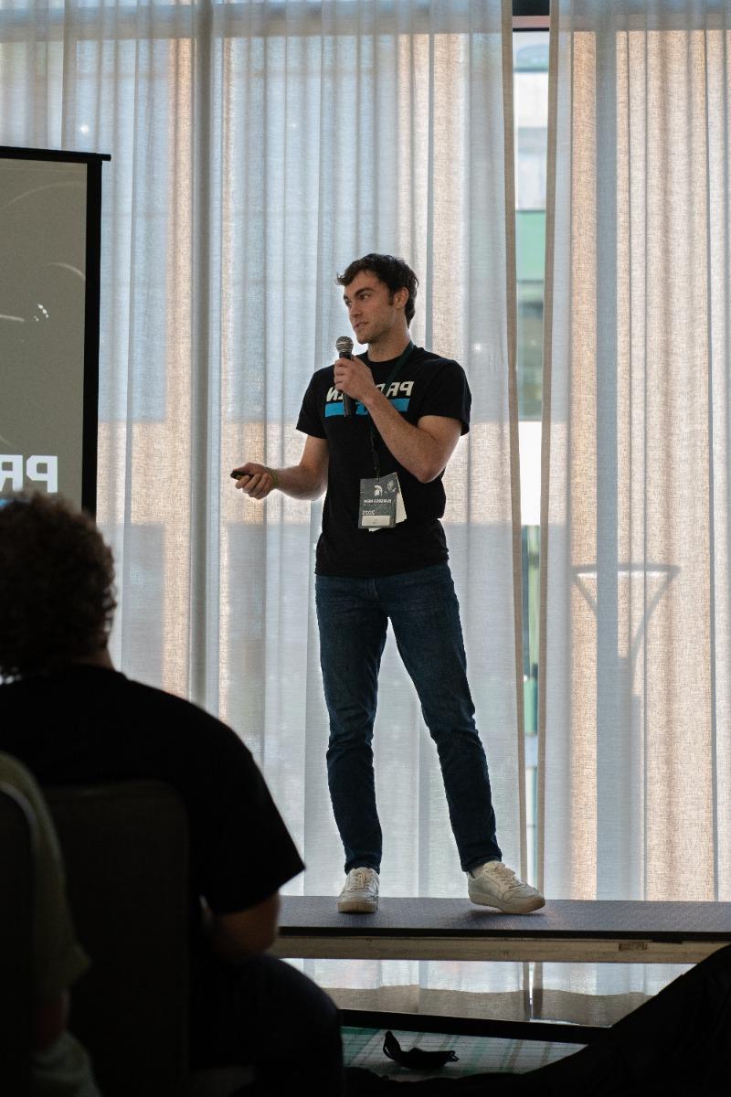 Paul 瑞斯 pitching his product on a stage wearing a Protein Pints t shirt