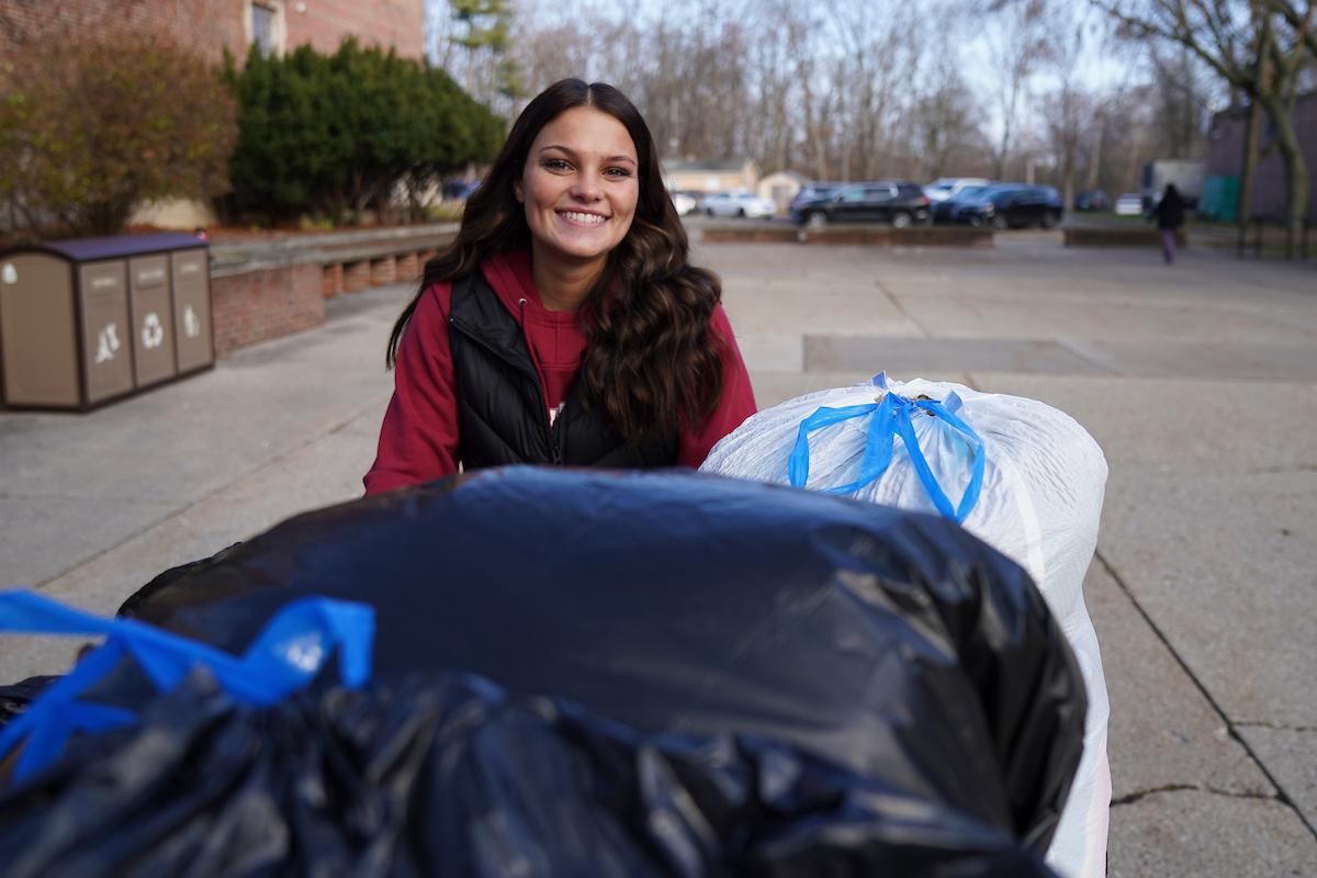 Student smiling with huge bag of donations