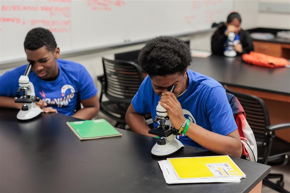 Two students look into microscopes