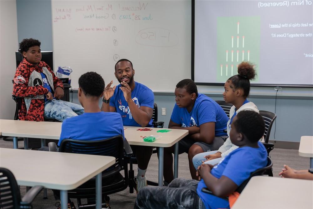 Students and teacher speaking around a table in a classroom